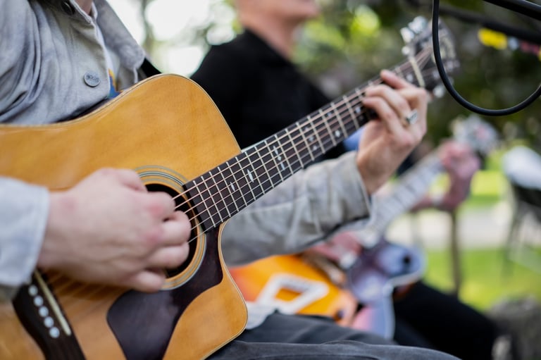 An intimate perspective captures the intricate fingerwork of a guitarist's hands on the fretboard and strumming the strings, conveying the passion and skill involved in live music creation.