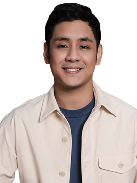 Smiling Asian man wearing a beige button-up shirt over a dark blue shirt, portrait on white background
