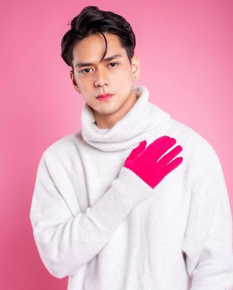 Young man wearing white turtleneck sweater with bright pink gloves against pink background