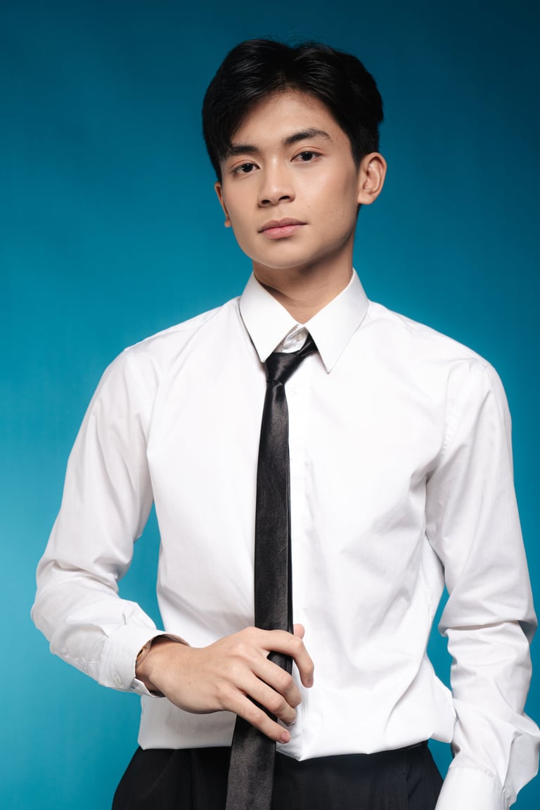Young Asian man in white dress shirt and black tie against teal background, professional headshot