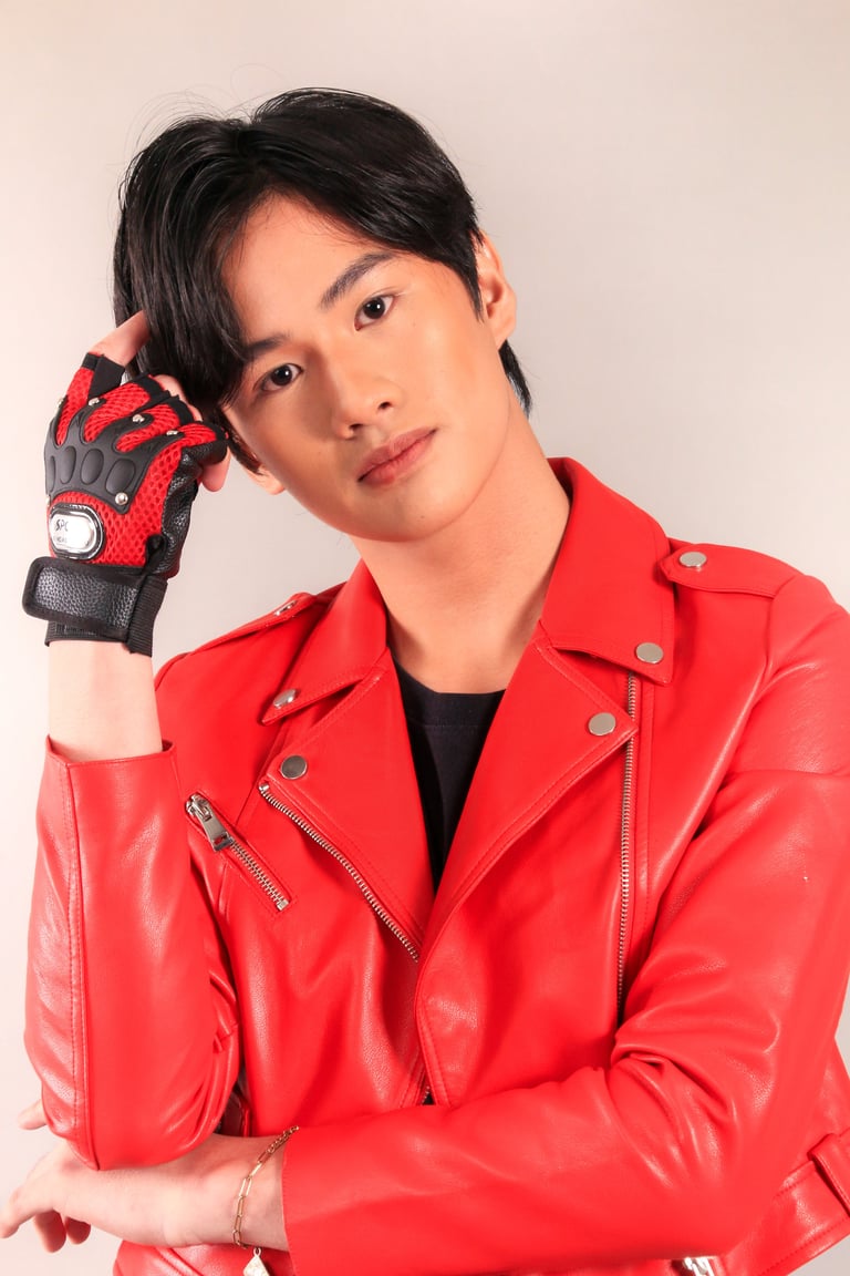 Young person wearing a bright red leather jacket and red paw print gloves, posing against a neutral beige background
