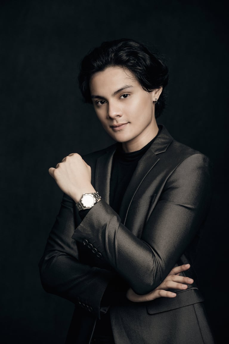 Professional portrait of a man in dark blazer with watch, posing confidently against black background