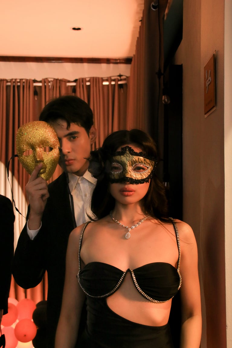 Two people wearing decorative masks at a formal event, posing together indoors