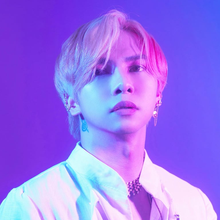 Portrait of a person with blonde hair wearing a white shirt against a purple and blue gradient background with neon lighting