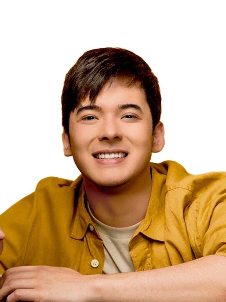 Young man in bright yellow shirt smiling at camera against white background