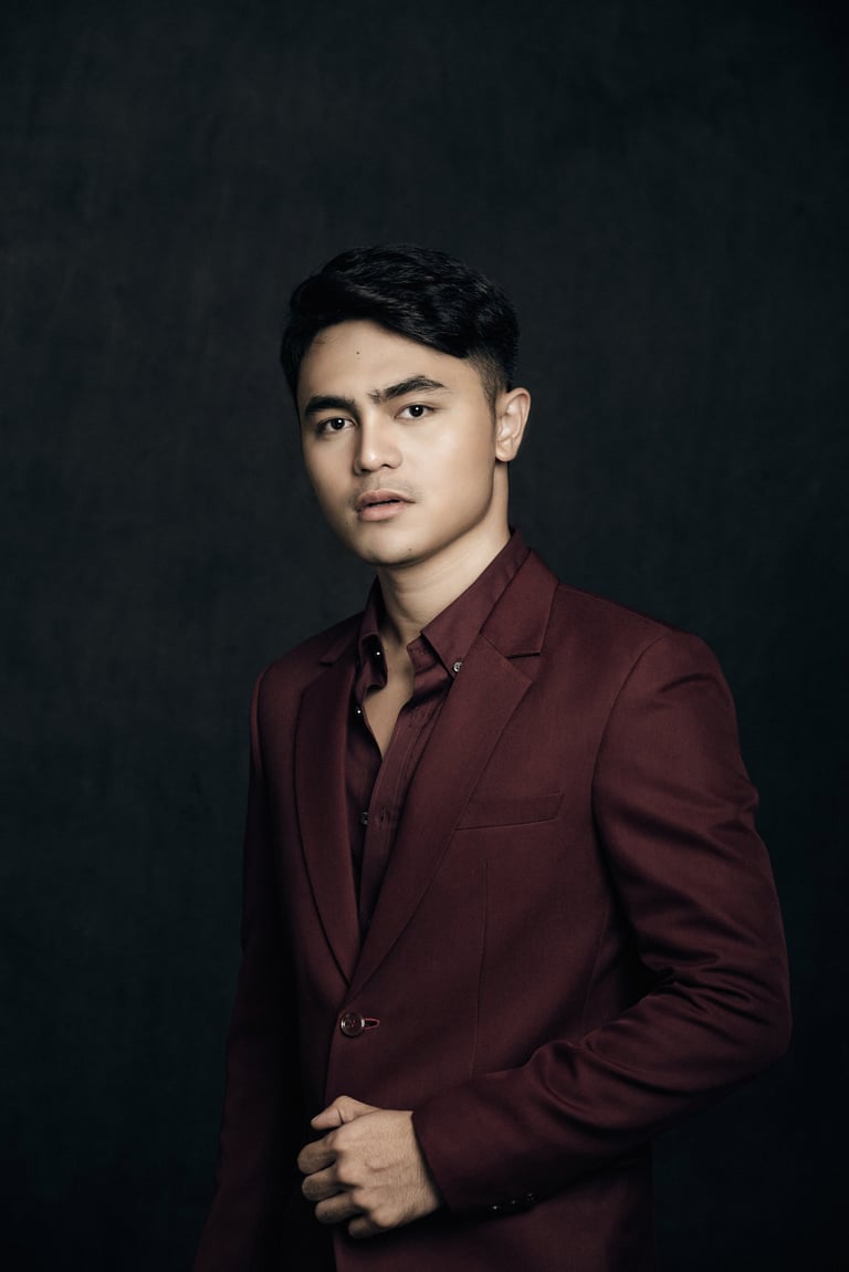 Young man in burgundy blazer against dark background, professional portrait style photo
